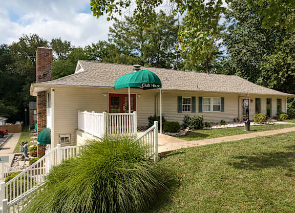 A white house with a green umbrella on the front porch.