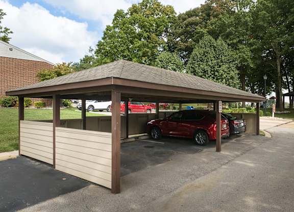 A covered parking area with a red car parked in it.