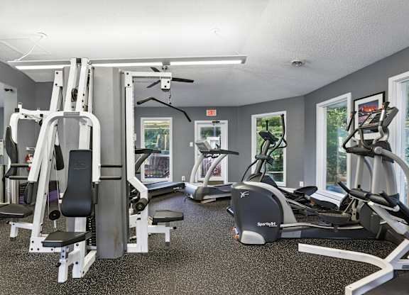 A gym with a variety of equipment including treadmills, weight machines, and a television.