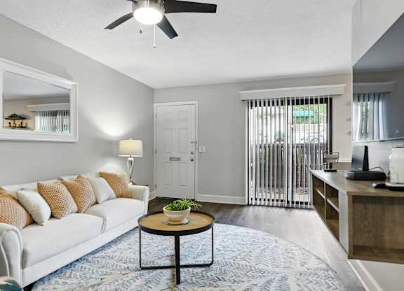 A living room with a white couch and a round table in the center.