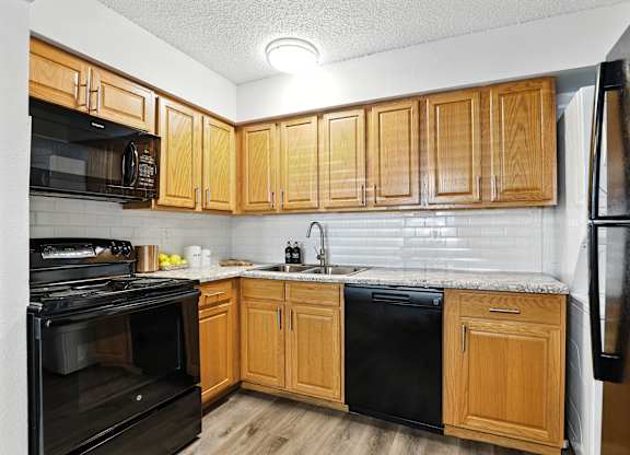 A kitchen with wooden cabinets and black appliances.