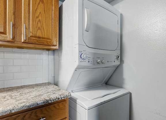 A white dryer is on top of a white washer in a kitchen.