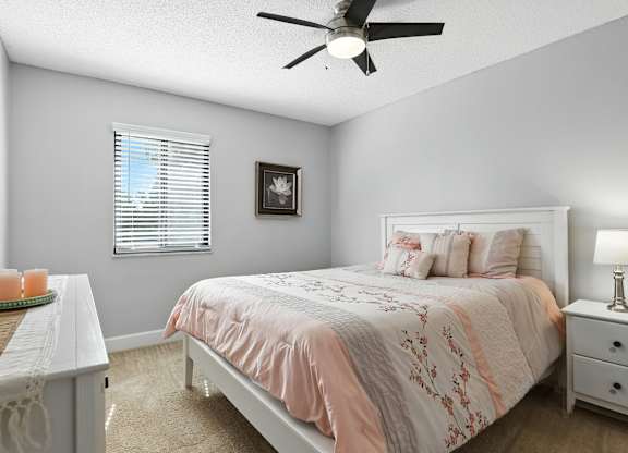 A bedroom with a bed, nightstand, and a table with a tray on it.