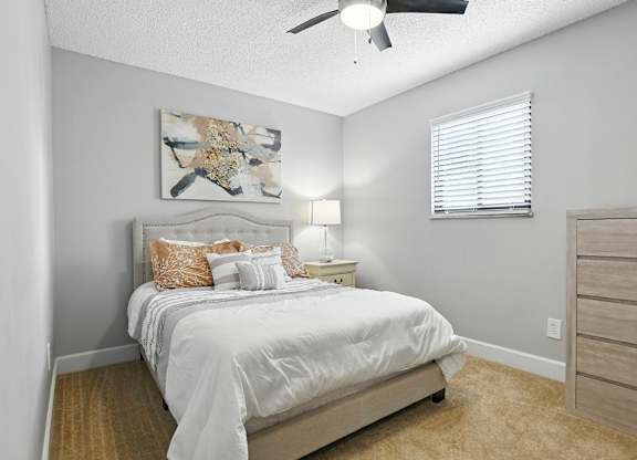 A bedroom with a bed, nightstand, and a painting on the wall.