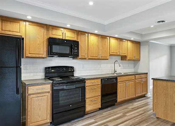 A kitchen with wooden cabinets and black appliances.