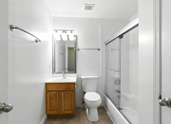 A white bathroom with a toilet, sink, and shower.