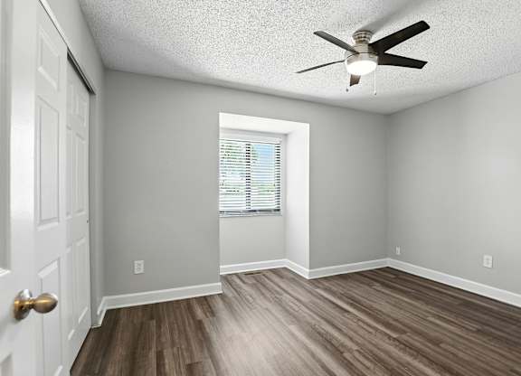 A room with a ceiling fan and a door.