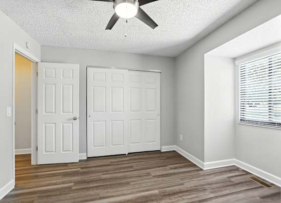 A room with a ceiling fan and two white doors.