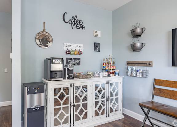 A coffee bar with a wooden bench and a wall hanging sign.
