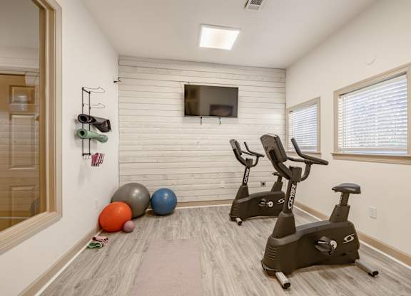 A room with a wooden floor and a wall-mounted TV with a white frame.