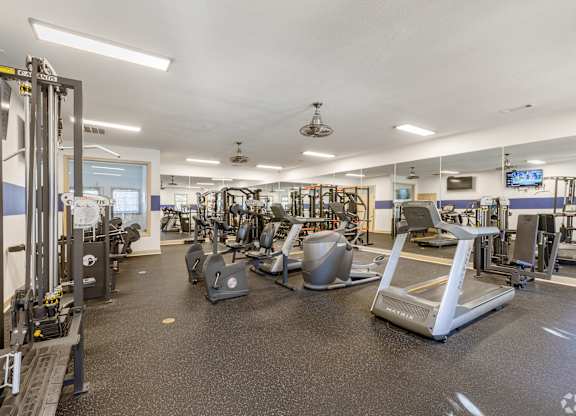 A gym with a variety of equipment including treadmills, weights, and exercise machines.