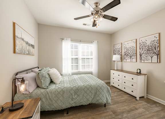 A bedroom with a bed, dresser, and a ceiling fan.