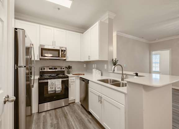 A modern kitchen with white cabinets and stainless steel appliances.