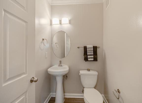 A white bathroom with a toilet, sink, and mirror.