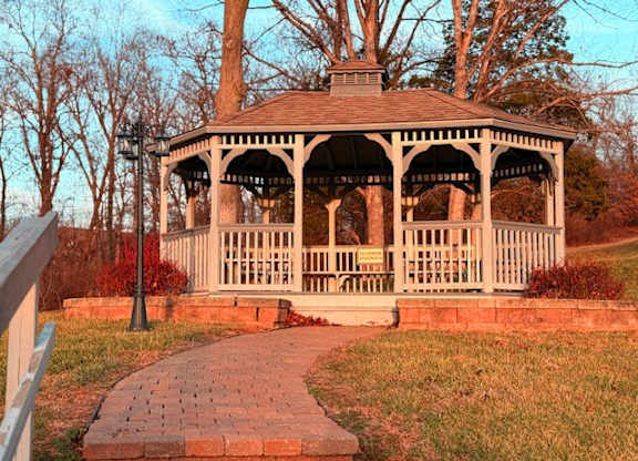 A gazebo with a brick walkway in front of it.