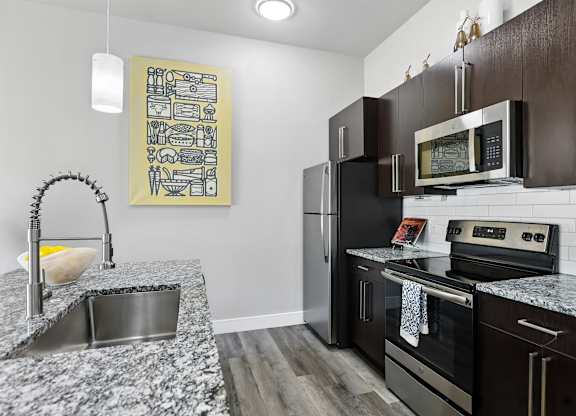 A kitchen with a granite countertop and a fridge.