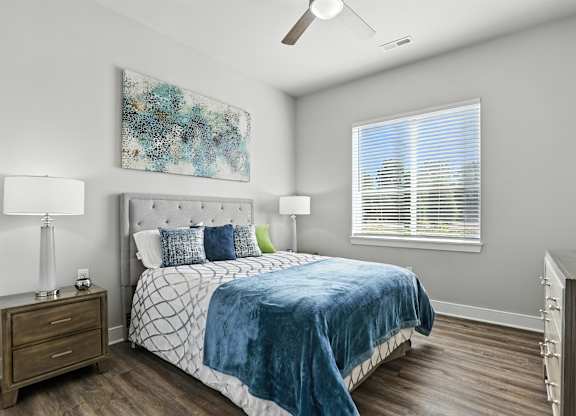 A bedroom with a bed, nightstand, and a painting on the wall.