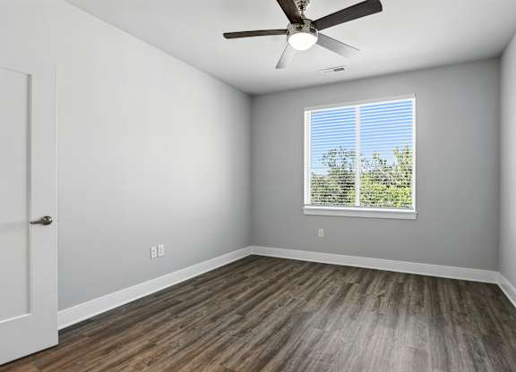 A room with a ceiling fan and a window with blinds.