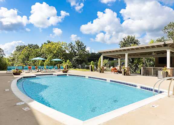 A large outdoor swimming pool with a pavilion and sun loungers.