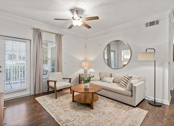 A living room with a white couch, a wooden coffee table, and a ceiling fan.