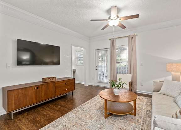 A living room with a wooden coffee table and a flat screen TV mounted on the wall.