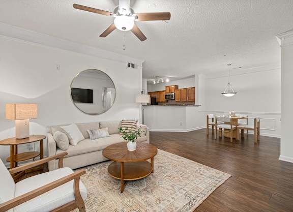 A living room with a white couch, a wooden coffee table, and a ceiling fan.