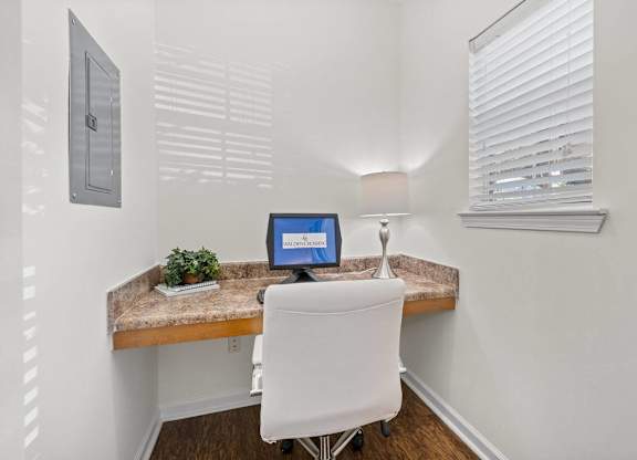 A small desk with a computer and a plant on it.