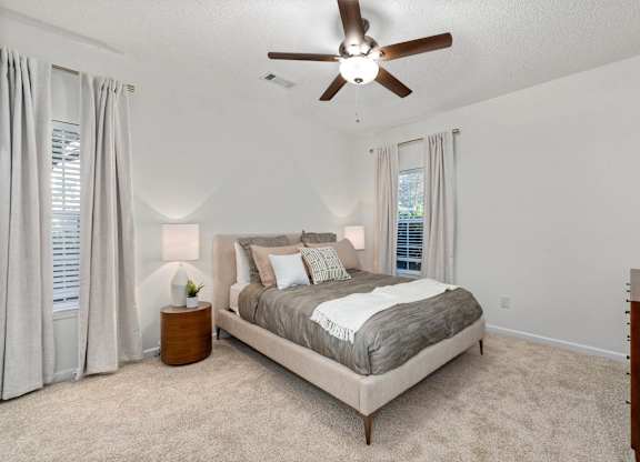 A bedroom with a large bed and a ceiling fan.