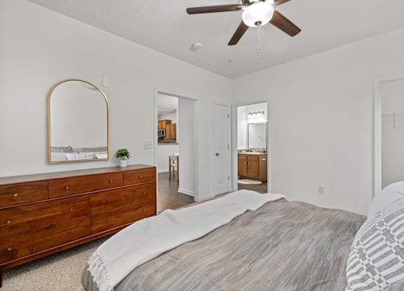 A bedroom with a large bed and a dresser with a mirror.