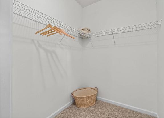 A white closet with a wire shelf and a basket on the floor.