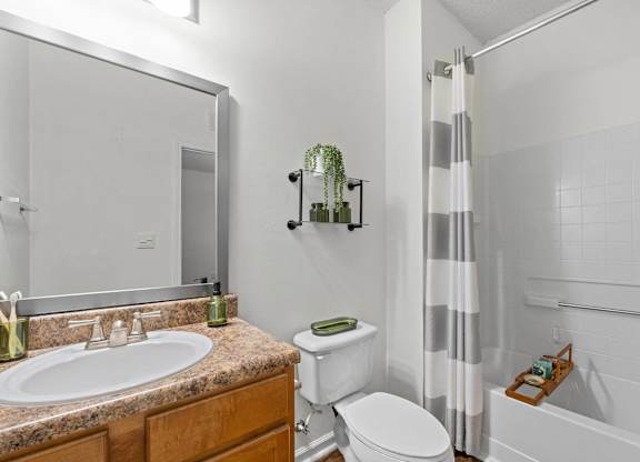 A bathroom with a white toilet and a striped shower curtain.