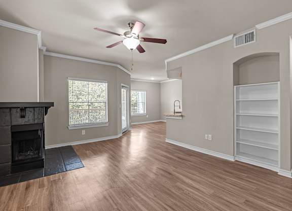 A living room with a fireplace and a ceiling fan.