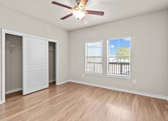 A room with a ceiling fan and a window with blinds.