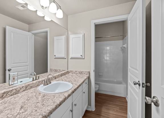 A bathroom with a sink, mirror, and shower.