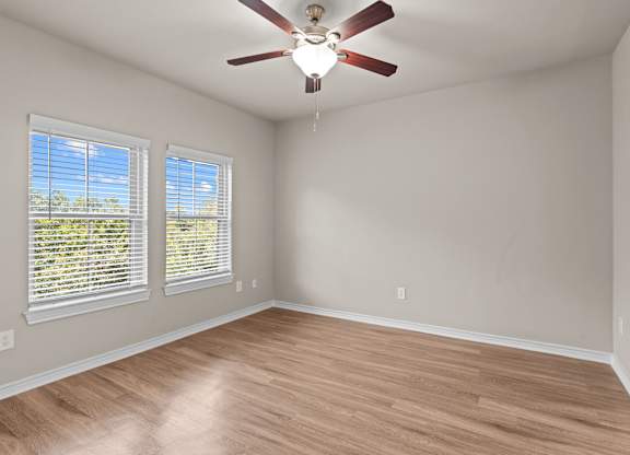 A room with a ceiling fan and wooden flooring.