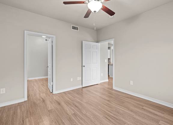 A room with a ceiling fan and two doors.