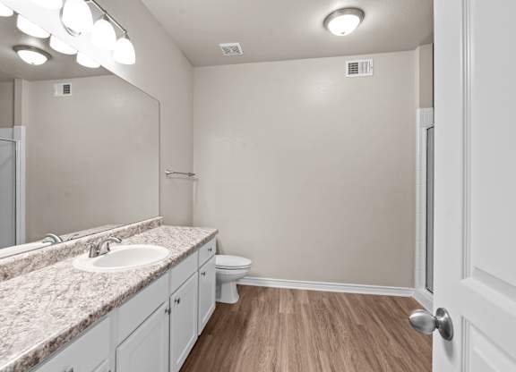 A bathroom with a marble countertop and white cabinets.