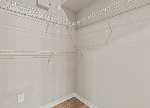 A white wall with a light switch and a wooden floor.