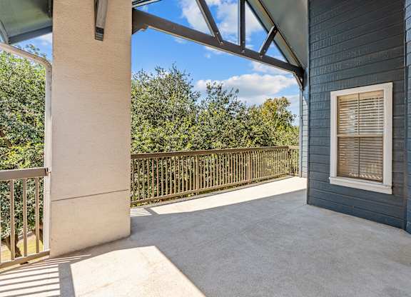 A balcony with a metal railing and a concrete floor.