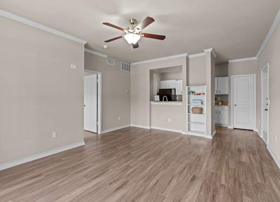 A room with a ceiling fan and wooden flooring.