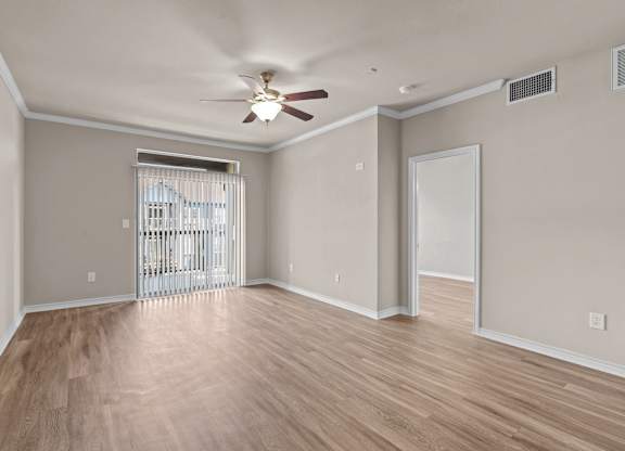 A room with a ceiling fan and wooden flooring.
