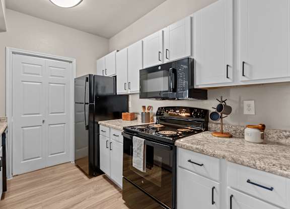 A kitchen with black appliances and white cabinets.