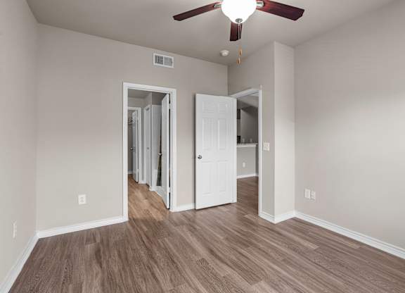A room with a ceiling fan and two open doors.