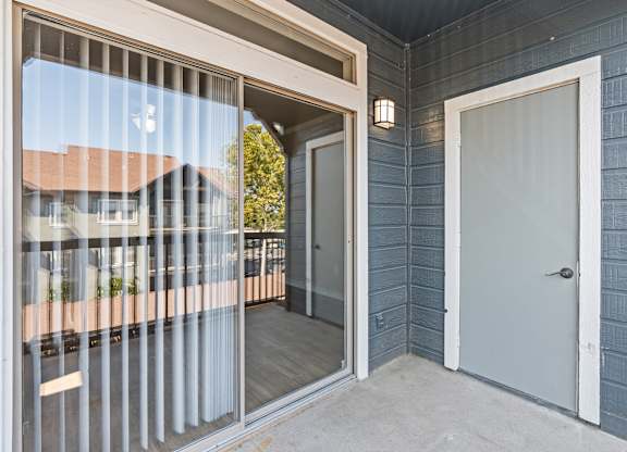 A balcony with a glass door and a white door.