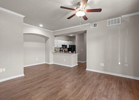A room with a ceiling fan and wooden flooring.