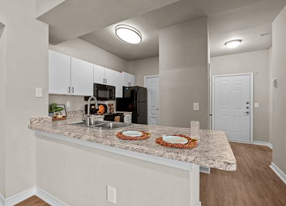 A kitchen with a granite countertop and white cabinets.