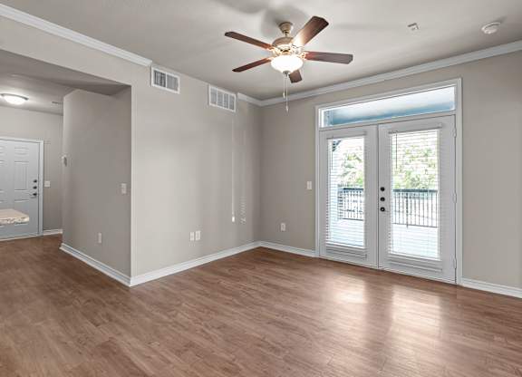 A room with a ceiling fan and sliding glass doors.