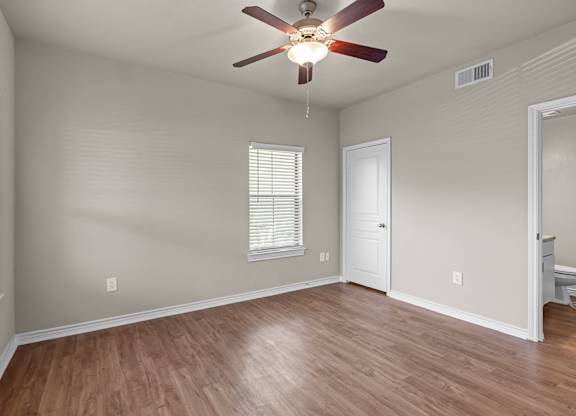 A room with a ceiling fan and wooden flooring.
