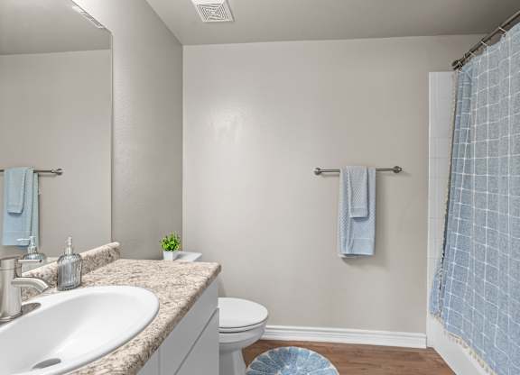 A bathroom with a white sink and a blue shower curtain.