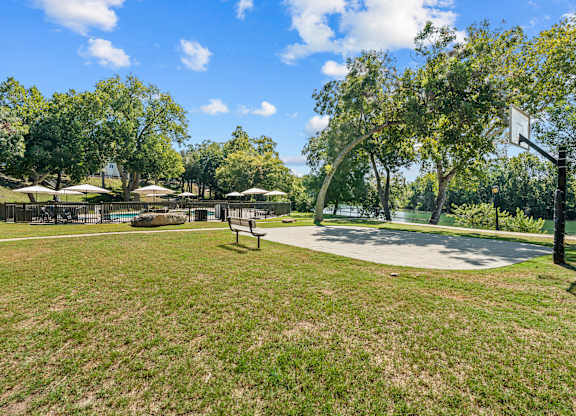 A park with a basketball court and a bench.